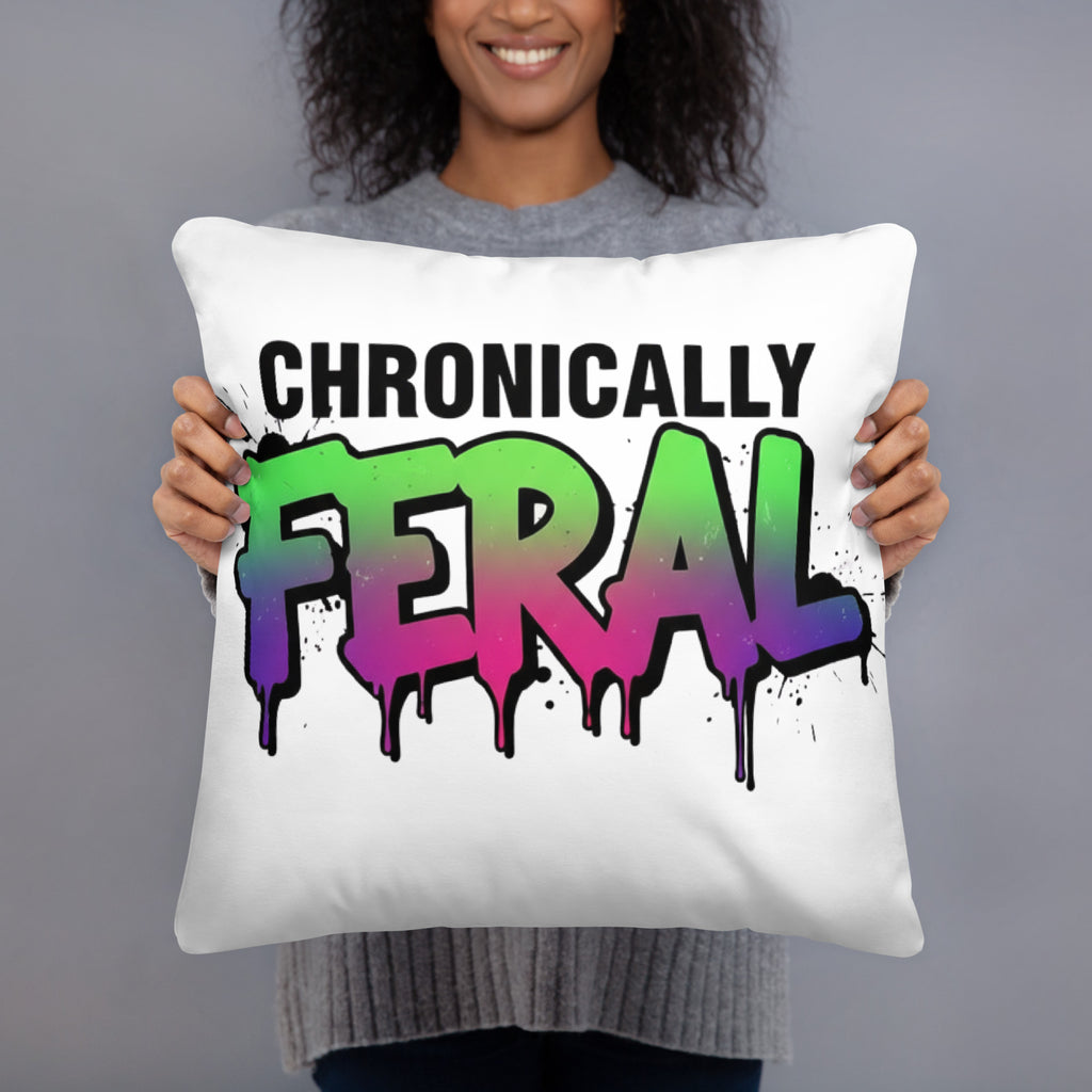 White square throw pillow with "CHRONICALLY" in black block letters and "FERAL" in large bold graffiti lettering with a green-to-purple rainbow gradient, heavy paint drips, and ink splatter. Feral as Fhawk™.