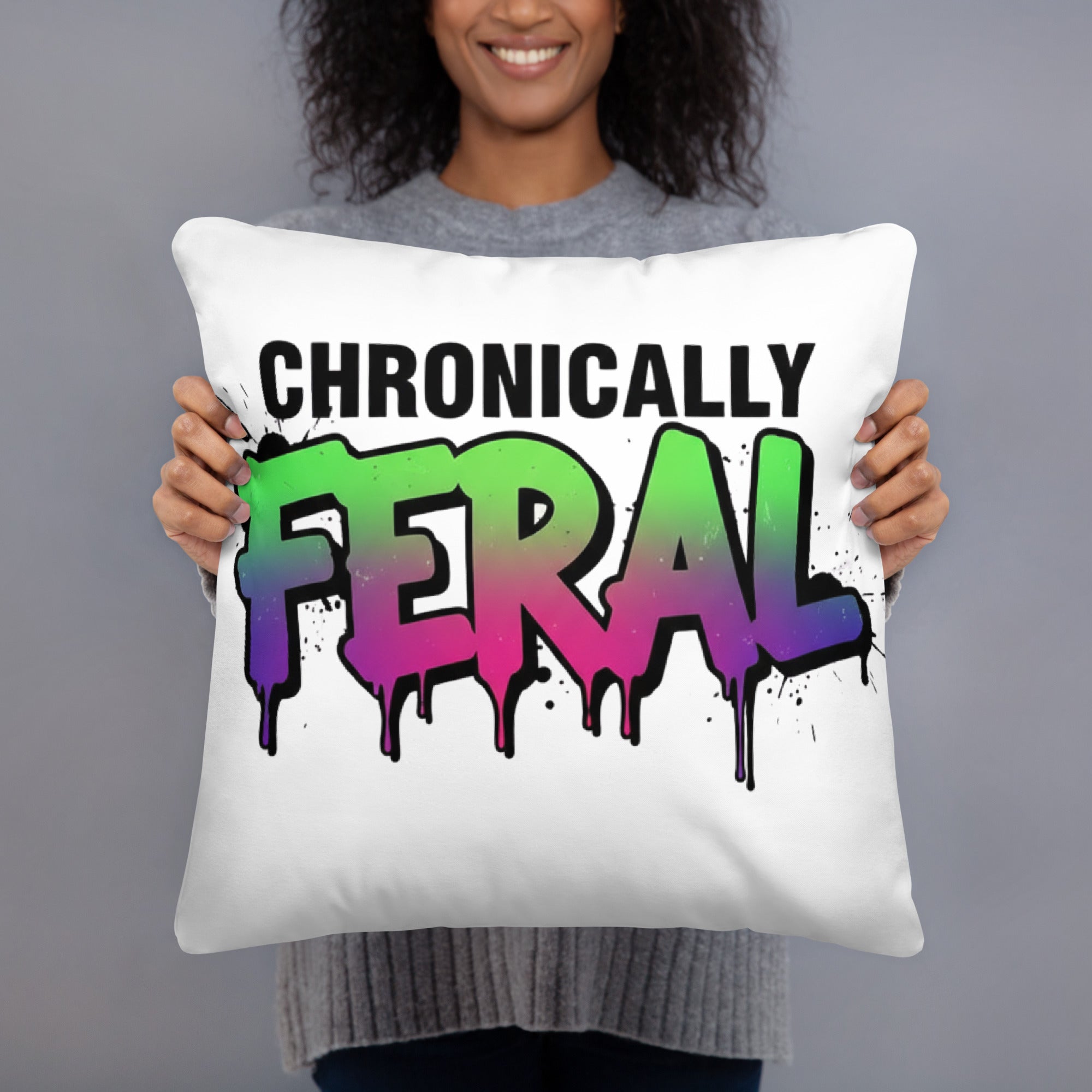 White square throw pillow with "CHRONICALLY" in black block letters and "FERAL" in large bold graffiti lettering with a green-to-purple rainbow gradient, heavy paint drips, and ink splatter. Feral as Fhawk™.
