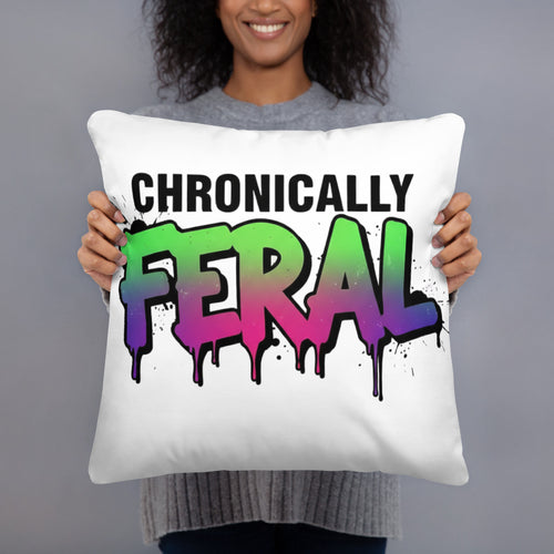 White square throw pillow with "CHRONICALLY" in black block letters and "FERAL" in large bold graffiti lettering with a green-to-purple rainbow gradient, heavy paint drips, and ink splatter. Feral as Fhawk™.